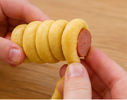 Wrapping cornmeal dough around a hot dog
