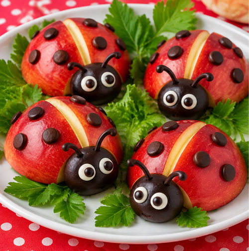 Red apple ladybugs decorated with chocolate spots and edible faces