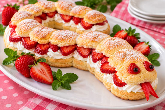 Strawberry shortcake shaped like a snake with strawberries and whipped cream