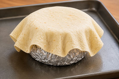 Flour tortilla shaped over a foil ball