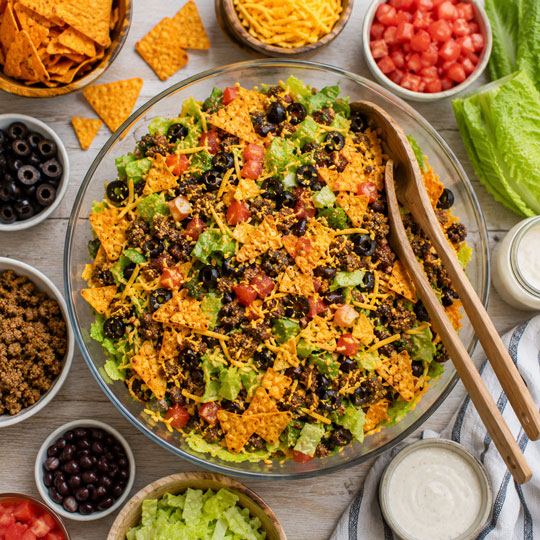 Doritos taco salad with seasoned beef lettuce tomatoes cheddar cheese and nacho cheese chips