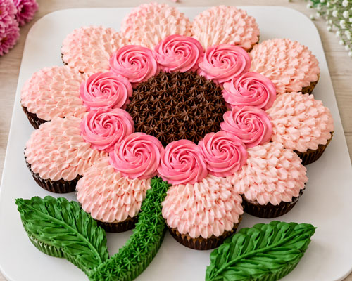 finished flower pull apart cupcake cake with pink frosting petals and green leaves