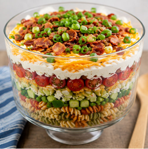 Seven layer pasta salad in a clear glass bowl